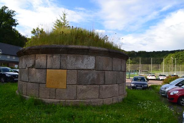 Gallo-römisches Grabmal (Replikat des Originalfundes, der bei den Bauarbeiten zum Sportplatz entdeckt wurde) auf dem Parkplatz der Sportanlage.
